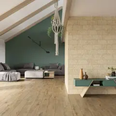 Nowoczesny salon z szarą sofą, zieloną ścianą i kamienną facjatą. Drewniana podłoga i wisząca roślina dodają przytulności.