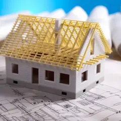 Model domu na planach architektonicznych, z widoczną konstrukcją dachu. Zastanawiasz się, ile kosztuje adaptacja projektu?
