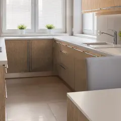 Nowoczesna kuchnia z frontami szafek w naturalnej okleinie imitującej drewno. Jasne blaty i eleganckie uchwyty.