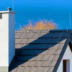 Dach domu z kominem i instalacją piorunochronu.