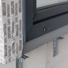 Szczegół montażu okna z użyciem taśmy paroszczelnej i uchwytów, kluczowy element ciepłego montażu okien.