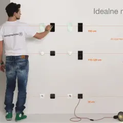 Mężczyzna pokazuje na jakiej wysokości gniazdka są idealne: 150 cm dla informacji, 110-120 cm dla akcji, 30 cm dla zasilania.