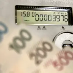 Zbliżają się wysokie rachunki za prąd. Licznik pokazuje zużycie, a banknoty 50, 100, 200, 500 zł sugerują przyszłą cenę prądu za 1 kWh w 2026 roku.