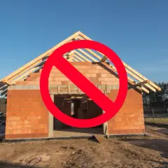 Czerwony znak zakazu na budowie domu z cegły. Nielegalizacja samowoli budowlanej jest niedopuszczalna.