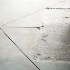 Szara posadzka z widoczną dylatacją. W jednym miejscu beton jest uszkodzony, odsłaniając podłoże.