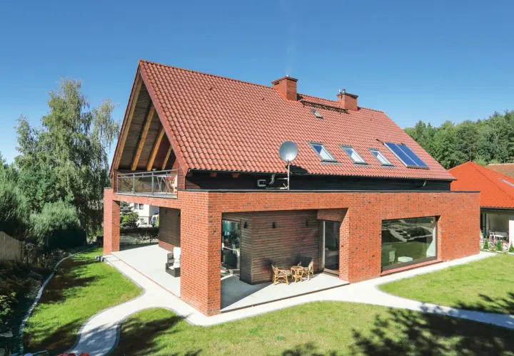 Nowoczesny dom z czerwonej cegły i dwuspadowym dachem. Szacowany koszt dachu dwuspadowego 100m2.