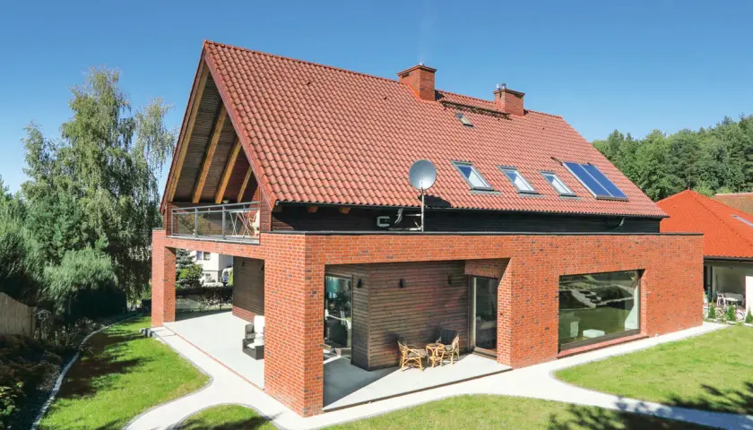 Nowoczesny dom z czerwonej cegły i dwuspadowym dachem. Szacowany koszt dachu dwuspadowego 100m2.