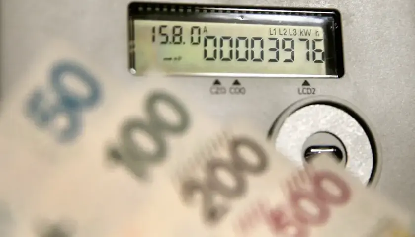 Zbliżają się wysokie rachunki za prąd. Licznik pokazuje zużycie, a banknoty 50, 100, 200, 500 zł sugerują przyszłą cenę prądu za 1 kWh w 2026 roku.