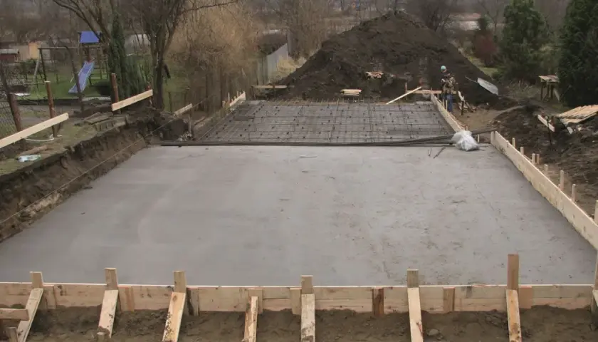Budowa fundamentów: świeżo wylany strop monolityczny, zbrojenie czeka na beton.