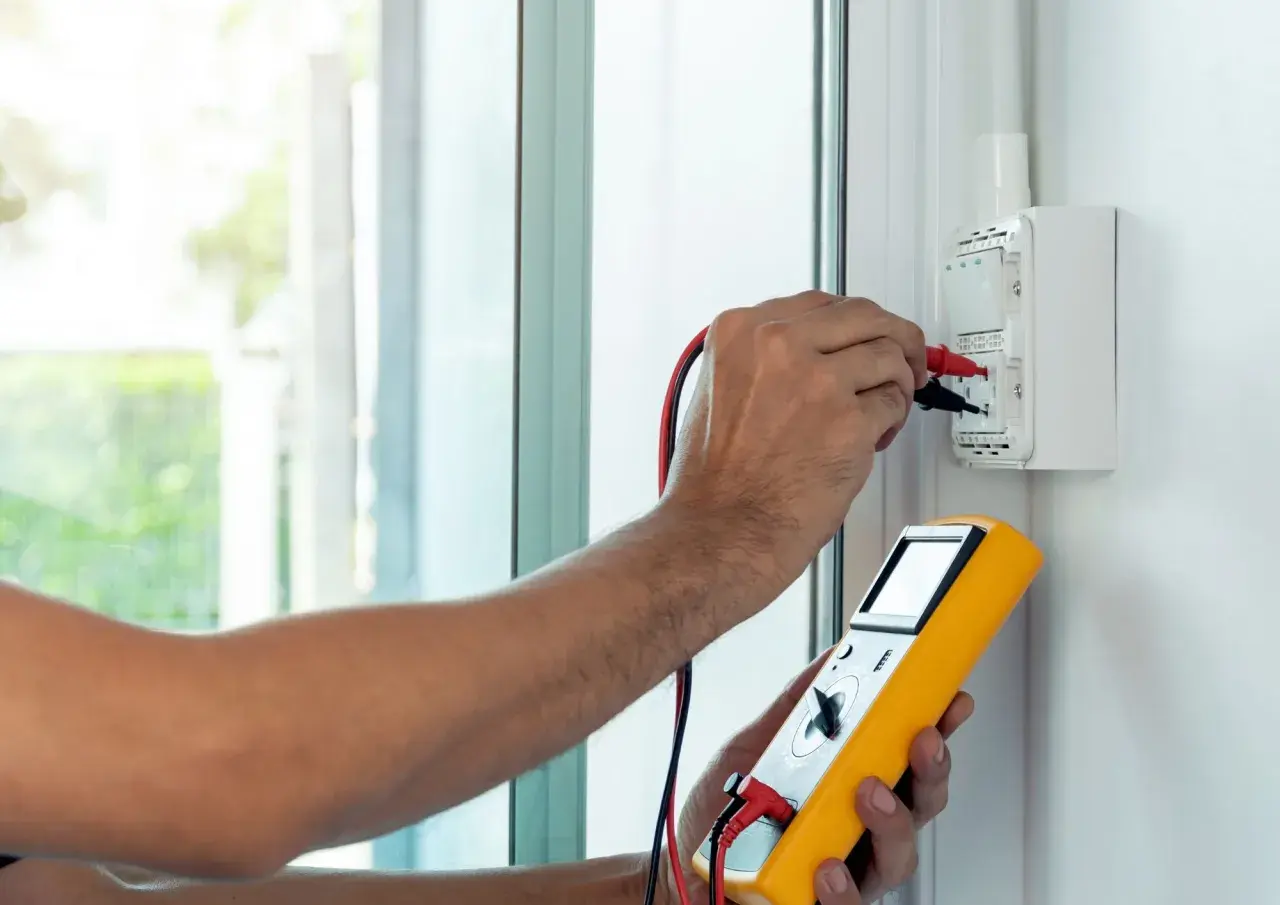 Elektryk mierzy impedancję pętli zwarcia za pomocą żółtego miernika.
