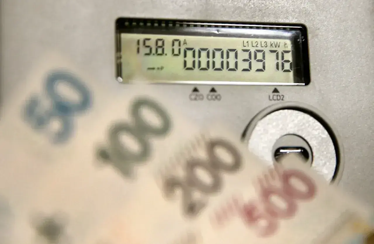 Zbliżają się wysokie rachunki za prąd. Licznik pokazuje zużycie, a banknoty 50, 100, 200, 500 zł sugerują przyszłą cenę prądu za 1 kWh w 2026 roku.