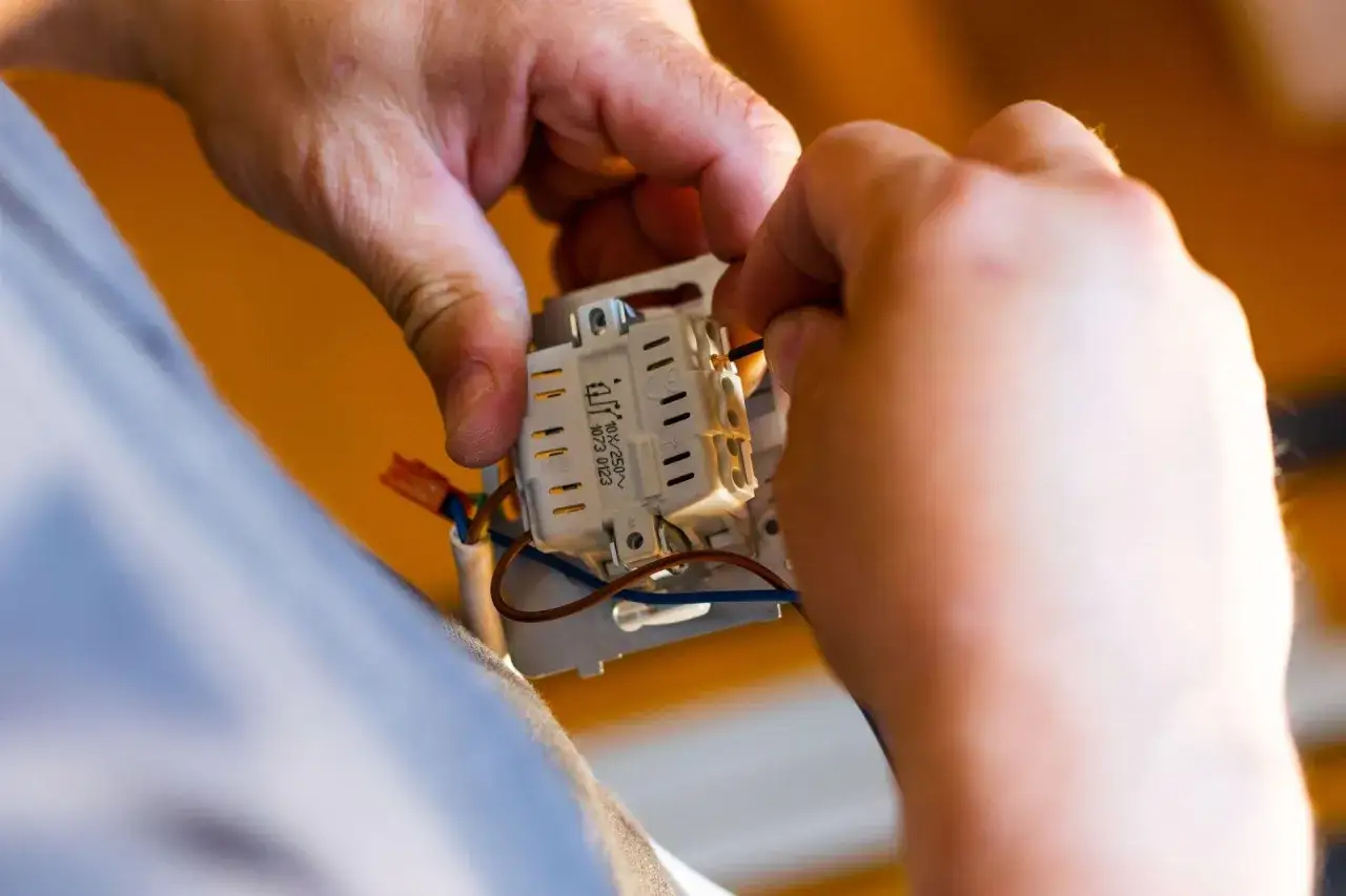 Ręce montują gniazdko elektryczne. Sprawdź montaż gniazdka cena i zamów fachowca.