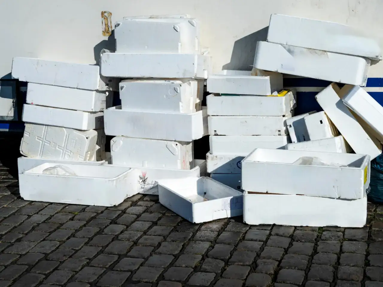 Stosy białych pojemników ze styropianu, często używanych do transportu ryb. Czy styropian to plastik? To pytanie nurtuje wielu.